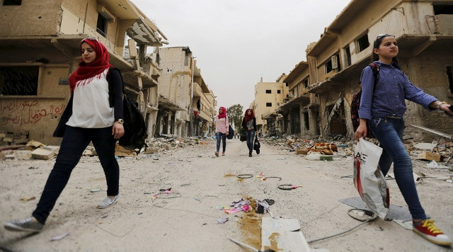 Người dân mang theo đồ đạc thu gom được từ ngôi nhà đổ nát trong chuyến trở về thành phố Palmyra, Syria hôm 9/4. Ảnh: Reuters.