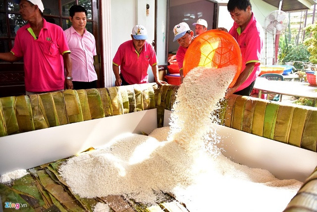 Sau khi lót lá, 4 chiếc vách được dựng xung quanh cách khuôn gần 10 cm. Tiếp đó, các công nhân tiến hành đổ lớp gạo nếp đầu tiên dày khoảng 5 cm.