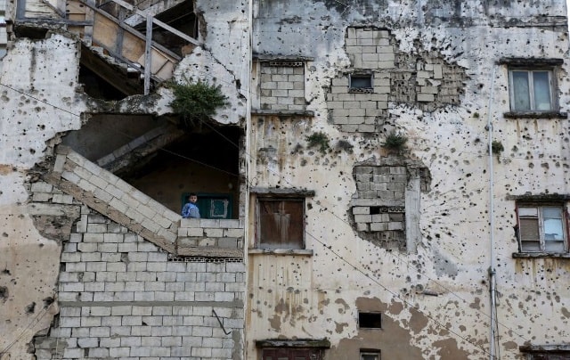 Cậu bé đứng trên cầu thang tòa nhà bị phá hủy ở Lebanon.