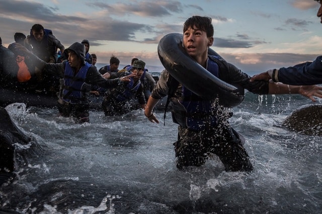 Hàng trăm người di cư từ Thổ Nhĩ Kỳ mừng rỡ khi đặt chân tới đảo Lesbos của Hy Lạp sau chuyến hành trình dài chống chọi với biển động và gió lớn. Lo sợ bị lật thuyền, một số người đã nhảy xuống dòng nước lạnh giá để bơi tới bờ. Bức ảnh của tác giả Tyler Hicks. Ảnh: New York Times