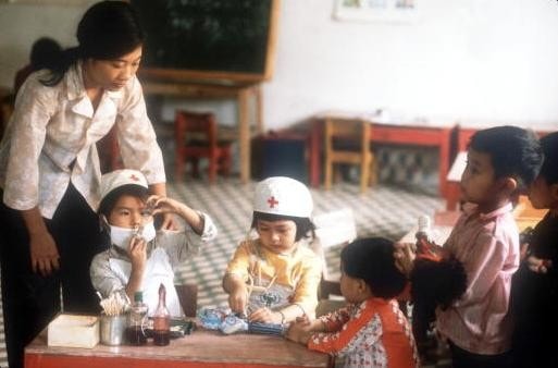 Cô giáo quan sát các em bé đóng vai bác sĩ và bệnh nhân tại một trường học ở thành phố Vinh.