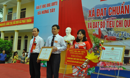 Đồng chí Hoàng Văn Phi - Bí thu Huyện ủy, Chủ tịch HĐND huyện Hưng Nguyên trao phần thưởng cho đại diện UBND và Trạm y tế xã Hưng Tây vì thành tích đạt chuẩn quốc gia về y tế