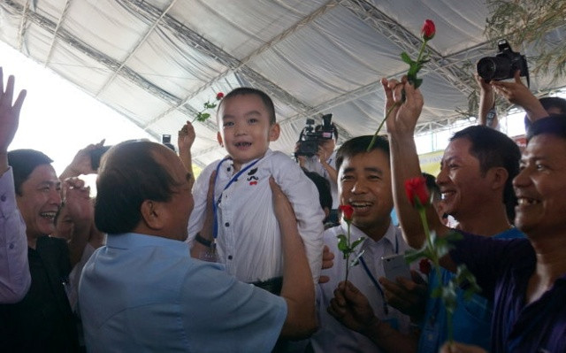 Thủ tướng Nguyễn Xuân Phúc bồng bé trai con của một công nhân - Ảnh: Hà Mi