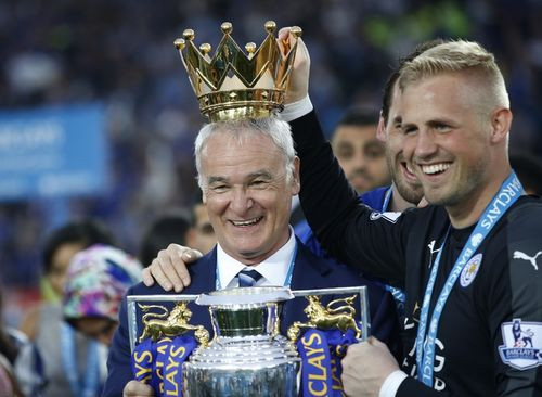 Ranieri cười tươi khi được học trò Kasper Schmeichel đặt lên đầu chiếc vương miện được gỡ ra từ cúp. Đây là danh hiệu vô địch quốc gia đầu tiên mà HLV 64 tuổi giành được sau 29 năm cầm quân.