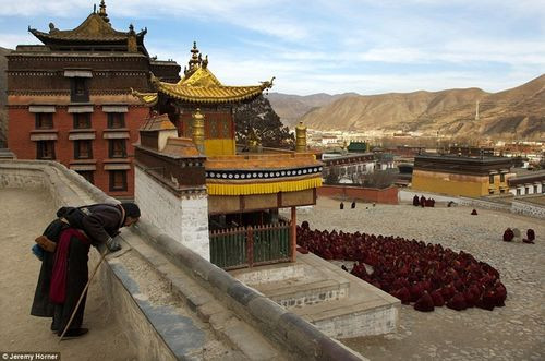 Một khách hành hương dừng lại cầu nguyện trong lúc đám đông các nhà sư đang tập trung ngoài sảnh chính tu viện Labrang. Được thành lập từ năm 1709, Labrang từng là nơi ở của hơn 4000 nhà sư nhưng hiện chỉ còn 1500 nhà sư.