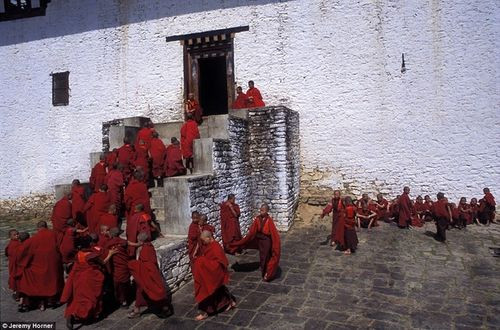 Trong những chiếc áo choàng màu đỏ rực rỡ, các nhà sư trở lại cầu nguyện sau giờ nghỉ trong sân tu viện Semtokha gần Thimphu, Bhutan.