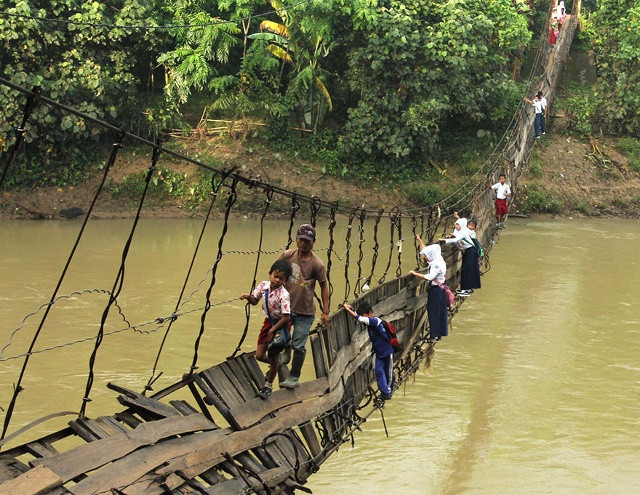Các em học sinh đang vượt qua một cây cầu treo bị hỏng ở Lebak, Indonesia. Sau khi câu chuyện được lan truyền, nhà sản xuất thép lớn nhất Indonesia đã xây một cây cầu mới để các em có thể qua sông an toàn. Ảnh: Reuters.