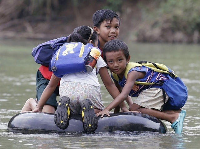 Học sinh tiểu học ở tỉnh Rizal, Philippines mang phao để vượt sông đi học. Ảnh: EPA.