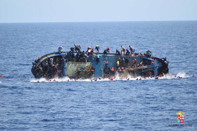 Những người di cư trèo lên thân thuyền khi con tàu đánh cá bị lật úp ngoài bờ biển Libya trước khi 2 tàu Hải quân Italia Bettica và Bergamini thực hiện công tác giải cứu (Ảnh: Lực lượng Hải quân Italia)