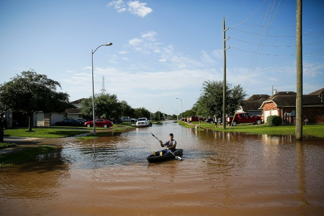 Anthony Perry (ở giữa), 1 người dân tại khu phố Rio Vista ở Richmond, bang Texas đã phải chèo thuyền ngay trên con phố Escambia Way Drive ngoài ngôi nhà của mình do bị ngập lụt vào ngày 31/5. Ảnh AP