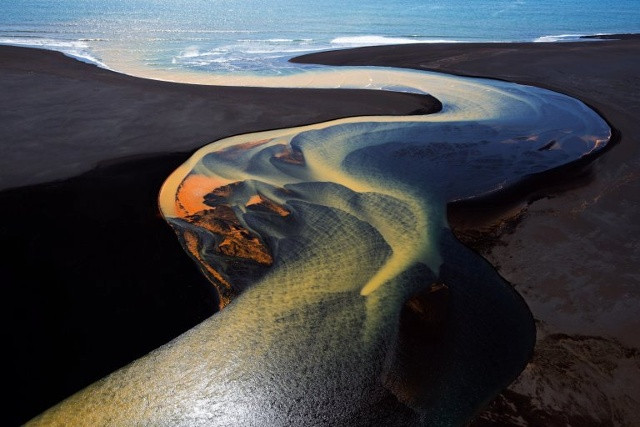 Nơi dòng sông đổ ra biển. (Ảnh: Stephen King)  Đây là một trong loạt bức ảnh chụp từ trực thăng xuống các vùng đồng bằng tuyệt vời ở Nam Iceland. Dòng sông uốn lượn tìm đường ra với đại dương. Màu sắc ấn tượng là nhờ các mỏ khoảng sản phản chiếu qua làn nước đóng băng trên hành trình đổ về biển. Tác giả đã may mắn ghi lại khoảnh khắc này vào một ngày nắng đẹp.
