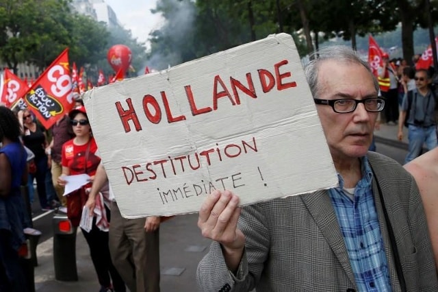 Một người biểu tình cầm tấm biển với nội dung “Tổng thống Hollande- Hãy  từ chức ngay lập tức”. Ảnh: Reuters