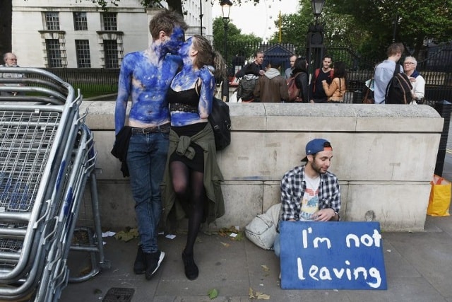 “Một cặp đôi vẽ lên cơ thể màu xanh lá cờ của EU bên ngoài số 10 Downing Street. Bên cạnh là một thanh niên với dòng chữ: “Tôi không ra đi”. (Getty).