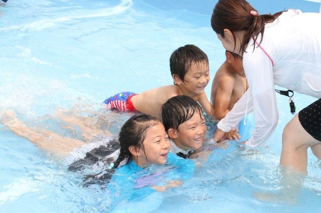 Bé tập bơi dưới sự hướng dẫn của giáo viên.