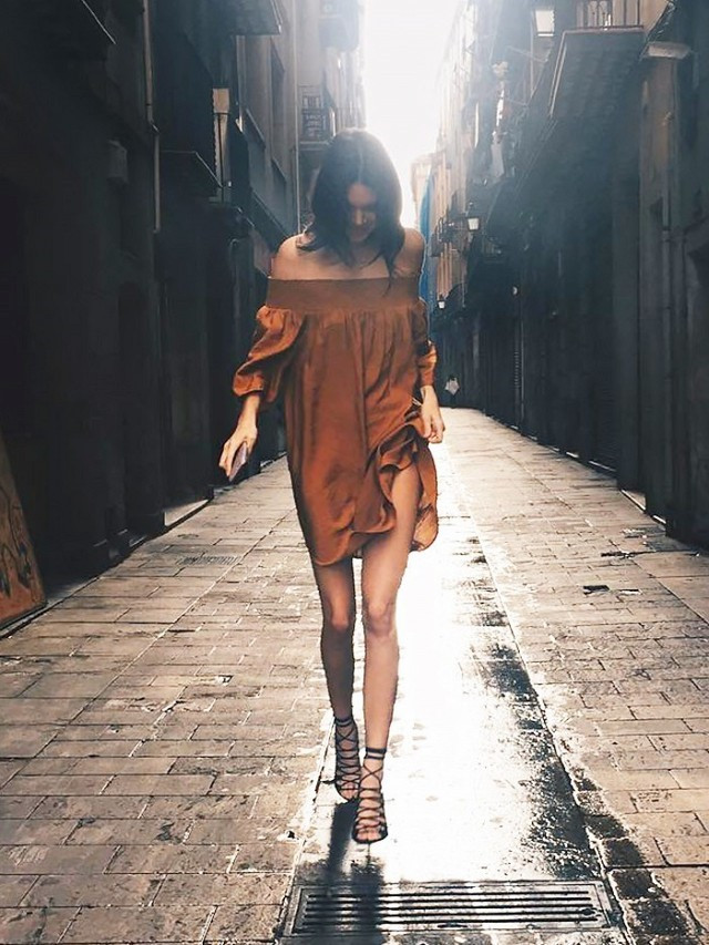 Kendall Jenner gây ấn tượng với kiểu váy trễ vai suông chất liệu mát mẻ mix cùng đôi giày cao gót buộc dây phong cách quen thuộc trên đường phố Barcelona.