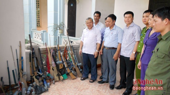 Linh mục Phan Văn Thắng (người đứng bên trái) bàn giao số súng tự chế và dao kiếm vừa thu hồi từ các con chiên trong giáo xứ cho cơ quan công an.