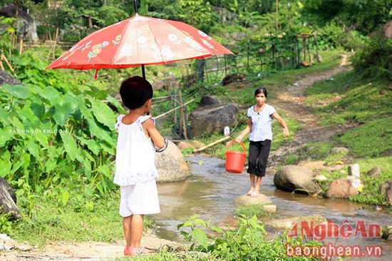 Xúc động với hình ảnh em bé ra bờ suối che ô đón mẹ đi lấy nước về.