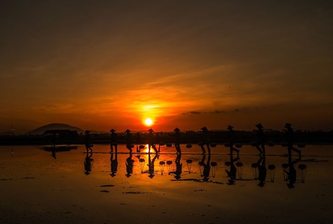 Ánh nắng lấp loáng soi bóng những người nông dân làm muối ở Nha Trang. Khoảnh khắc được chụp lại bởi nhiếp ảnh gia Arif Kugu. 