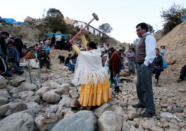 Một người phụ nữ cố gắng đập vỡ một tảng đá bằng một cái búa tạ trong lễ hội cầu may. Ảnh Reuters