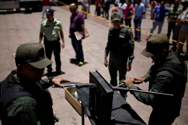 Lực lượng tự vệ quốc gia Venezuela thực hiện phá hủy súng tại Quảng trường thành phố Caracas. Ảnh: Reuters.
