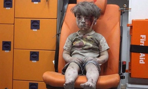 Tên em là Omran Daqneesh. Hình ảnh em lặng im ngồi trên ghế trong một chiếc xe cứu thương, toàn thân phủ kín bụi đất, được lan truyền rộng rãi trên các phương tiện truyền thông, là minh chứng rõ nét nhất cho thấy sức tàn phá khủng khiếp cũng như những ảnh hưởng sâu sắc của bóng ma chiến tranh đang bao phủ lên đất nước Syria, theo CNN. Daqneesh mới 5 tuổi, bằng đúng số năm chiến sự bùng phát ở Syria. Em sống với cha mẹ, anh trai và chị gái tại chính 