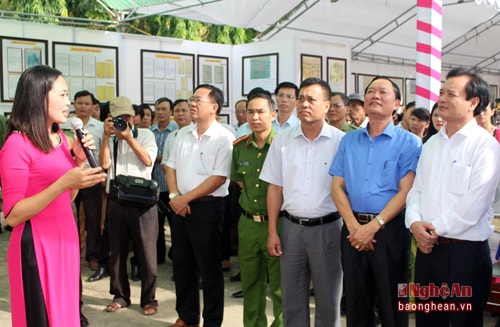 Các đại biểu nghe thuyết minh giới thiệu về các tư liệu trưng bày tại triển lãm.