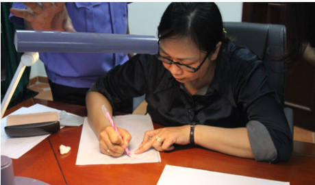 Bà Nguyễn Thị Thanh Vân đang thực nghiệm lại hành vi làm giả giấy tờ trước Cơ quan điều tra. Ảnh do cơ quan điều tra cung cấp