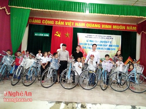 Đại diện lãnh đạo huyện Anh Sơn và nhà máy gạch tuynel Anh Sơn trao xe đạp cho các em học sinh.