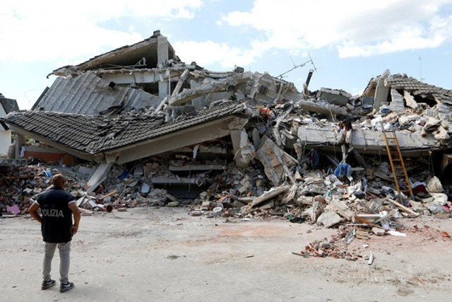Một nhân viên cứu hộ đứng trước một tòa nhà đổ sập sau động đất ở thị trấn Amatrice, miền trung Italy. Ảnh: Reuters.