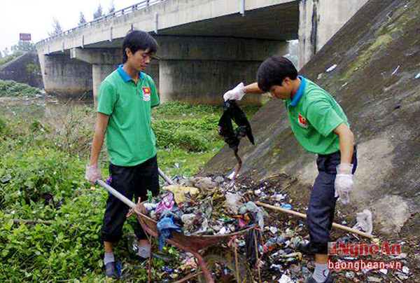 Anh Đinh Bùi Thương (Người cầm xe rùa) tham gia lao động dọn vệ sinh tại điểm nóng rác thải với Câu lạc bộ tình nguyện Nghi Lộc