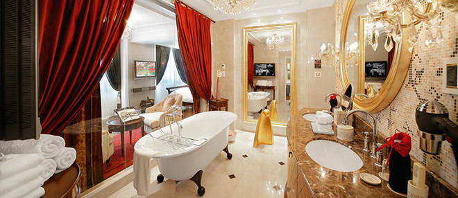 Phòng tắm được trang trí với tông màu chủ đạo là vàng và đỏ, lãng mạn, có bồn tắm đứng kiểu Pháp và tắm xông hơi. Không gian sáng, lấp lánh nhờ gương, đèn chùm, tường kính lớn.