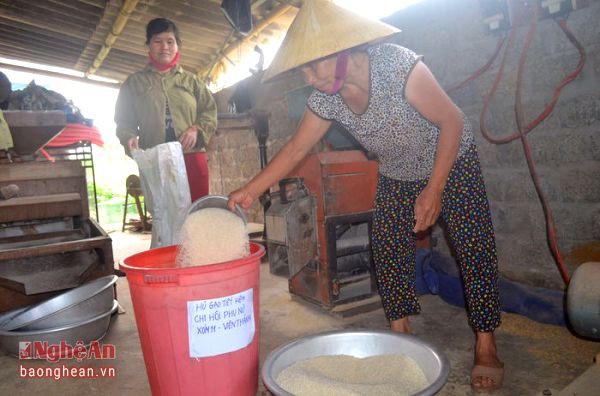 Bà con đóng góp gạo vào hũ gạo tình thương đặt tại cửa hiệu xay xát gạo của xóm.