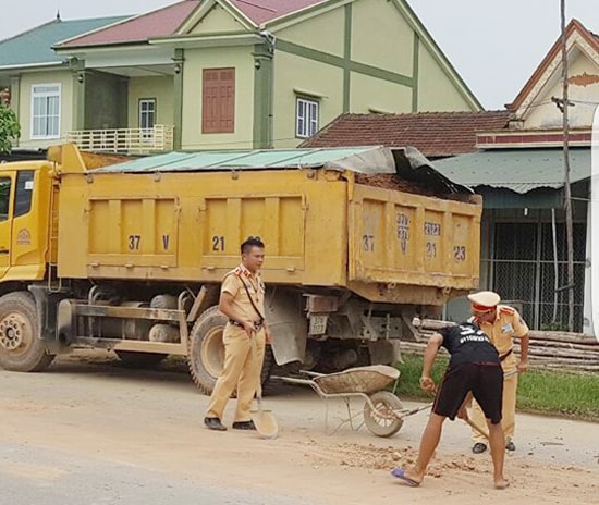 Hai chiến sỹ cảnh sát giao thông giúp chủ xe thu dọn đất đá vương vãi trên mặt đường. Ảnh: Facebook
