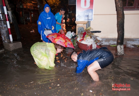  Người dân ở hai bên đường phải dùng tay móc rác đang chèn miệng cống để khơi thông giúp nước rút nhanh hơn