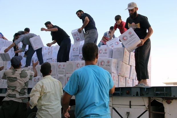 Người dân Syria dỡ hàng cứu trợ sau khi 48 xe tải chở hàng cứu trợ đi vào thị trấn Talbiseh miền bắc Homs do lực lượng nổi dậy kiểm soát hồi tháng 7/2016. Ảnh: AFP