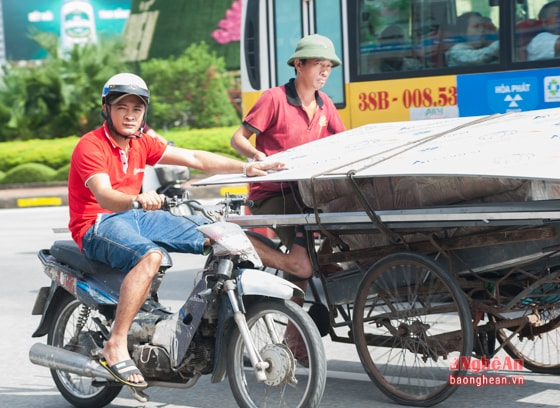 Nhờ một người đàn ông đi trên xe máy đẩy phụ, chiếc xích lô chở đủ loại hàng dài ngắn khác nhau lao vun vút trên đường Trần Phú đoạn Cầu Thông