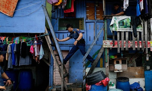 Cảnh sát di chuyển giữa các căn nhà trong một chiến dịch bài trừ ma túy ở khu ổ chuột tại Manila. Ảnh: Guardian