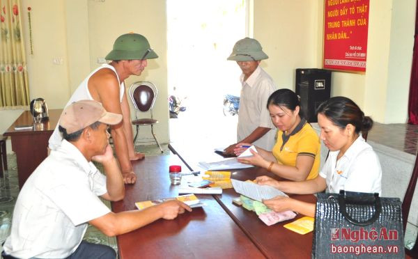 Cán bộ bưu điện và bưu tá xã chi trả bảo trợ xã hội tại Nhà văn hóa xã Quỳnh Giang (Quỳnh Lưu).