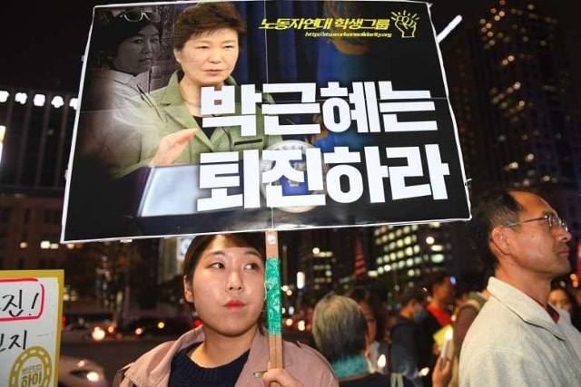 Người Hàn Quốc xuống đường ở Seoul đòi Tổng thống Park Geun Hye từ chức. Trong tấm bảng cô gái cầm là hình bà Park và Choi SoonSil (góc trái) - Ảnh: AFP