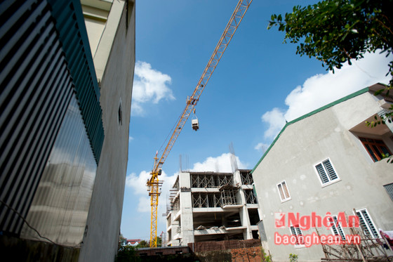 Mỗi lúc quay trở để cẩu những thùng bê tông nặng nề lên, cánh tay khổng lồ lại quét một vòng qua các mái nhà của những hộ gia đình sống xung quanh.