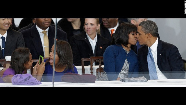 Obama hôn vợ trong buổi lễ diễu binh mừng ngày nhậm chức ở Washington. Con gái Sasha (trái) đang chụp ảnh cô chị gái Malia.