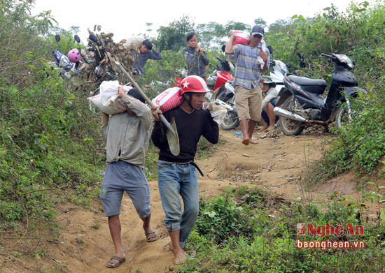 Những người đàn ông dùng bì tải để mang đất xuống bờ sông đãi.