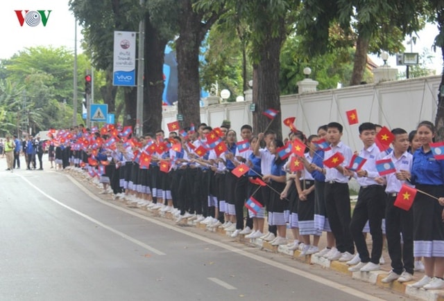 Dọc hai bên đường từ sân bay quốc tế Wattay về Phủ Chủ tịch, đông đảo quần chúng nhân dân các dân tộc Lào trong trang phục truyền thống, tay cầm cờ, hoa nồng nhiệt chào đón Tổng Bí Nguyễn Phú Trọng và Đoàn Đại biểu cấp cao Việt Nam.