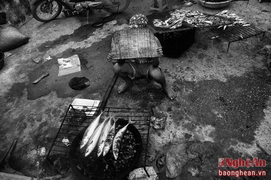 Một chú bé ngại ngần lấy quạt than che mặt khi thấy ống kính máy ảnh. Em cũng hăng hái ra phụ mẹ bán hàng trong ngày nghỉ lễ đông khách tới đền Cờn.