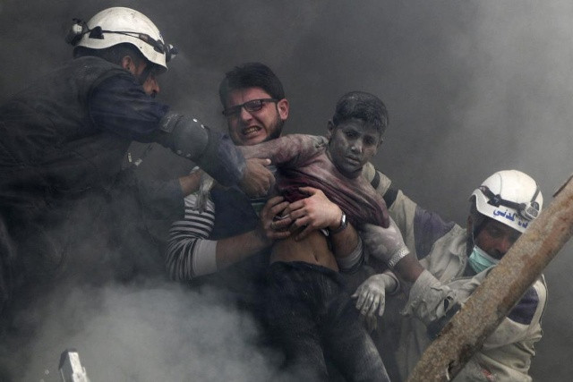 Đàn ông giải cứu một cậu bé từ dưới đống đổ nát sau những gì các nhà hoạt động cho biết là thùng nổ giảm lực lượng trung thành với Syria của Tổng thống Bashar Al-Assad trong khu phố Al-Shaar Aleppo ngày 06 tháng tư năm 2014. REUTERS