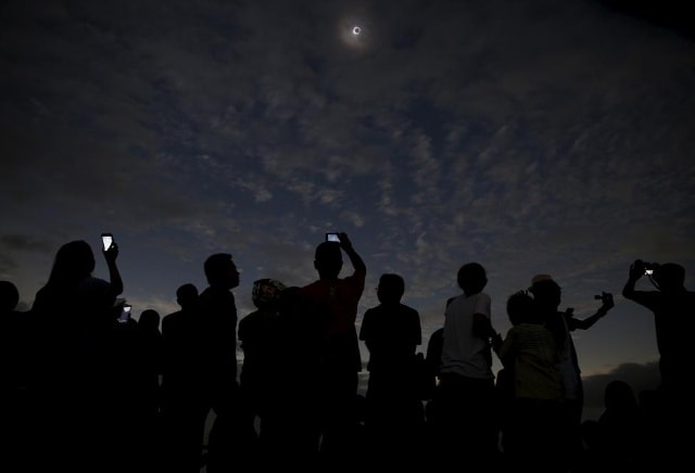 Mọi người xem và chụp ảnh nhật thực tại bãi biển trên đảo Ternate, Indonesia, March 2016. REUTERS /