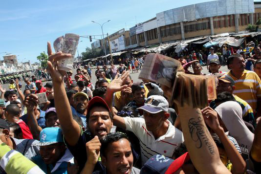 Người Venezuela cầm tiền đi biểu tình hôm 16/12. Ảnh: AFP