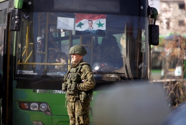 Lính Nga đứng gác gần một chiếc xe buýt sơ tán dân thường ở Aleppo. Ảnh Reuters.