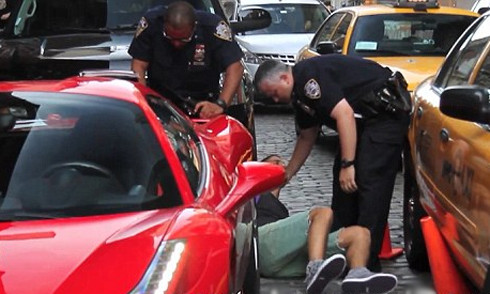 Chủ nhân siêu xe màu đỏ bị quật ngã và còng tay nằm trên đường. 