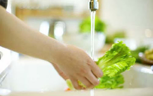 Rửa rau dưới vòi nước chảy để đảm bảo an toàn vệ sinh thực phẩm.